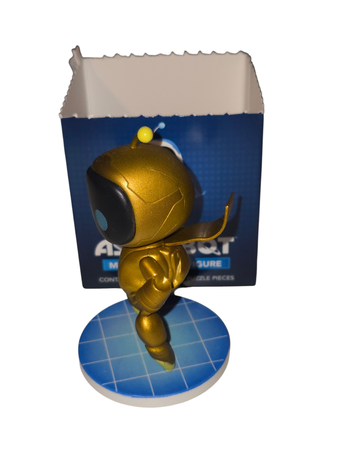 Side view of gold chase Astro Bot mystery vinyl figure on blue grid base