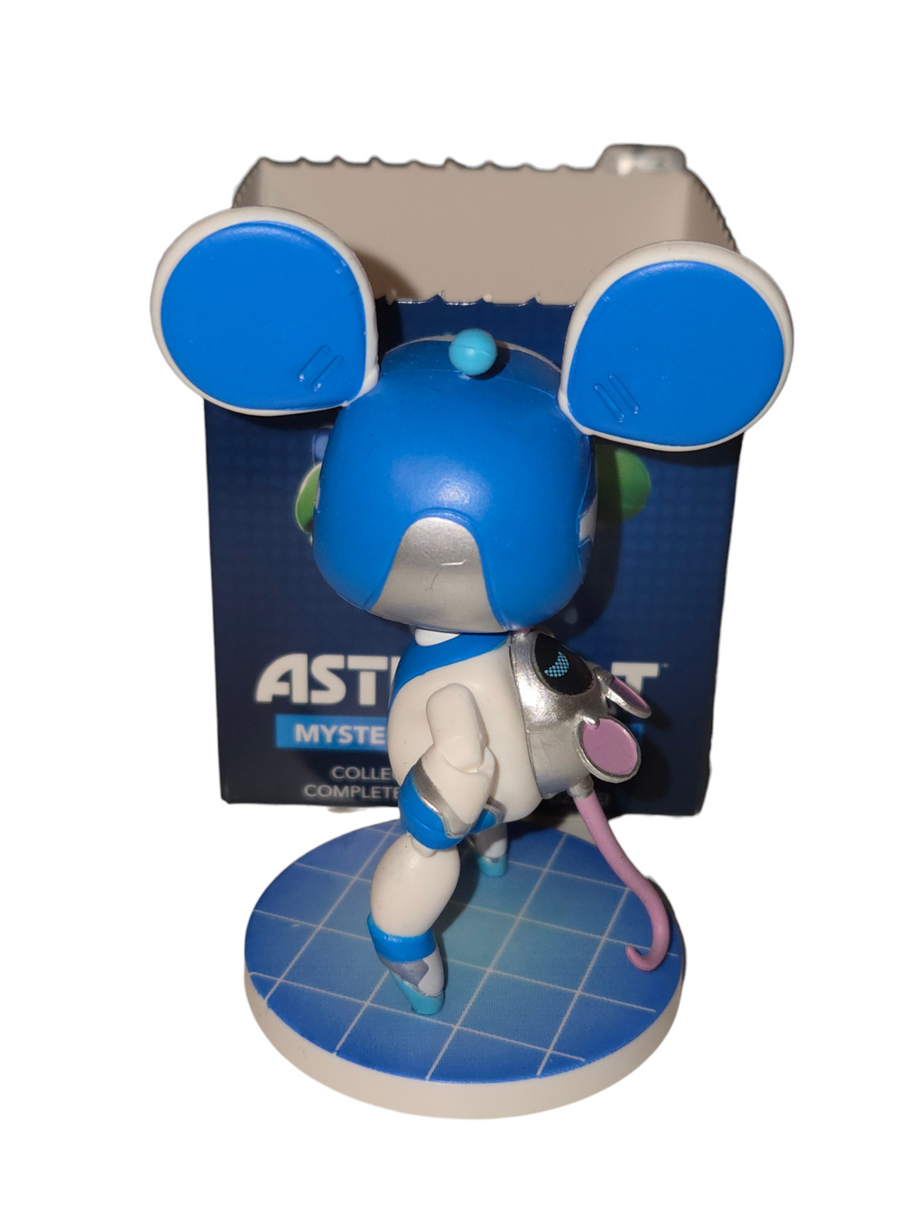 Rear view of Astro Bot and Mini Mimi figure showing blue mouse ears and pink tail on grid base