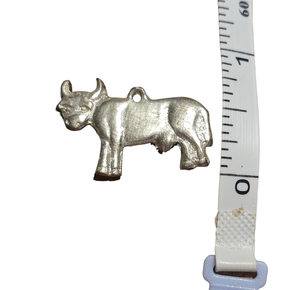 Vintage bull pendant beside measuring tape for scale