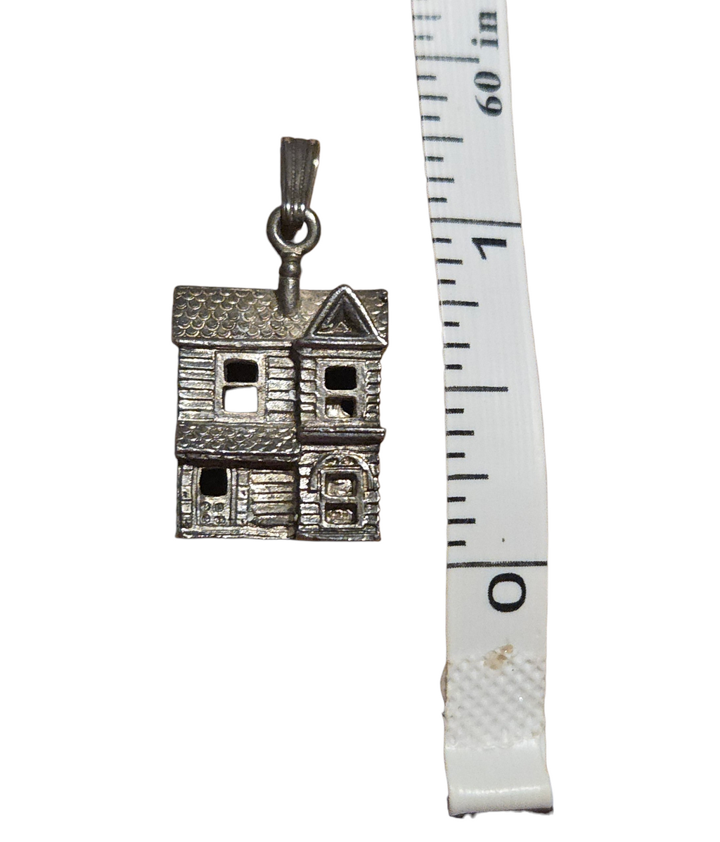 Dollhouse pendant beside measuring tape for scale