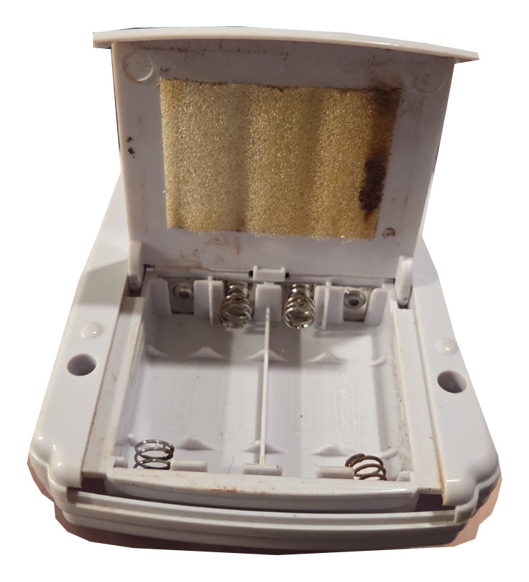 Open battery compartment showing remaining discoloration and corrosion staining