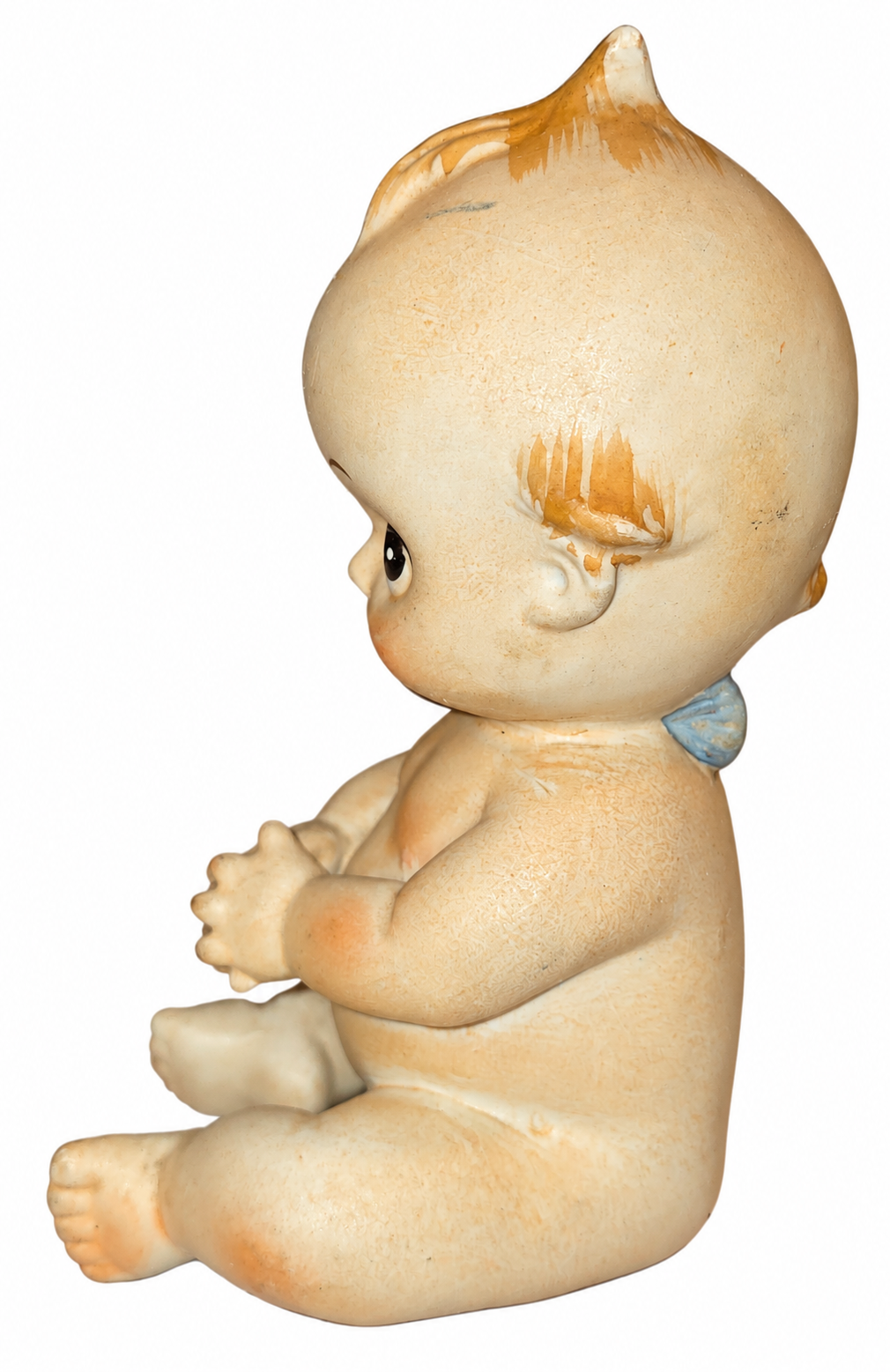 Vintage seated Kewpie ceramic figurine side view with original wear on white background